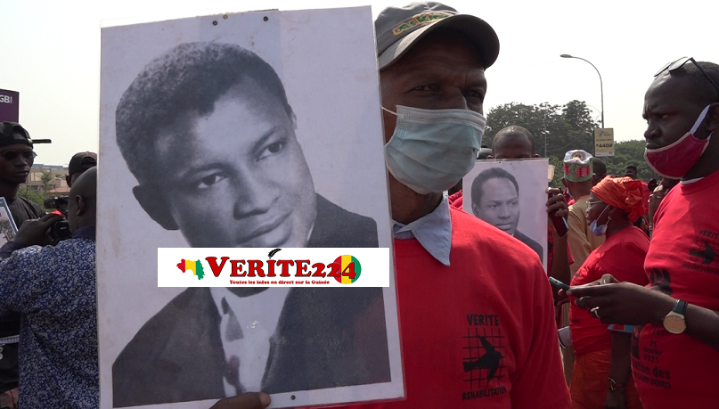 Un enfant d'une victime tenant le portrait de son père lors de la commémoration de la première pendaison du régime de Sékou Touré