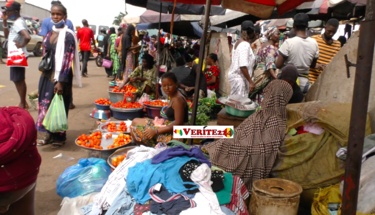 Des étalagistes assises sous les emprises de la route à Conakry